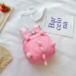 Zaino pre-scolastico rosa a forma di dinosauro con sfondo bianco e poster con scritte blu