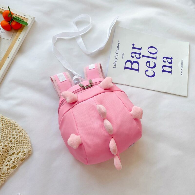 Zaino pre-scolastico rosa a forma di dinosauro con sfondo bianco e poster con scritte blu