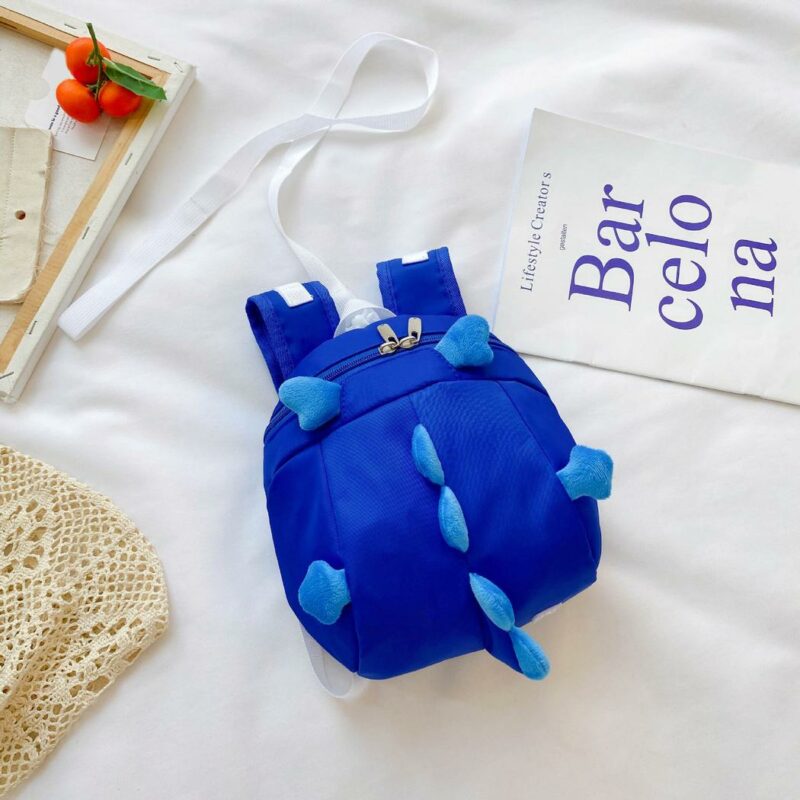 Zaino prescolare a forma di dinosauro blu con sfondo, letto bianco, poster con scritta blu