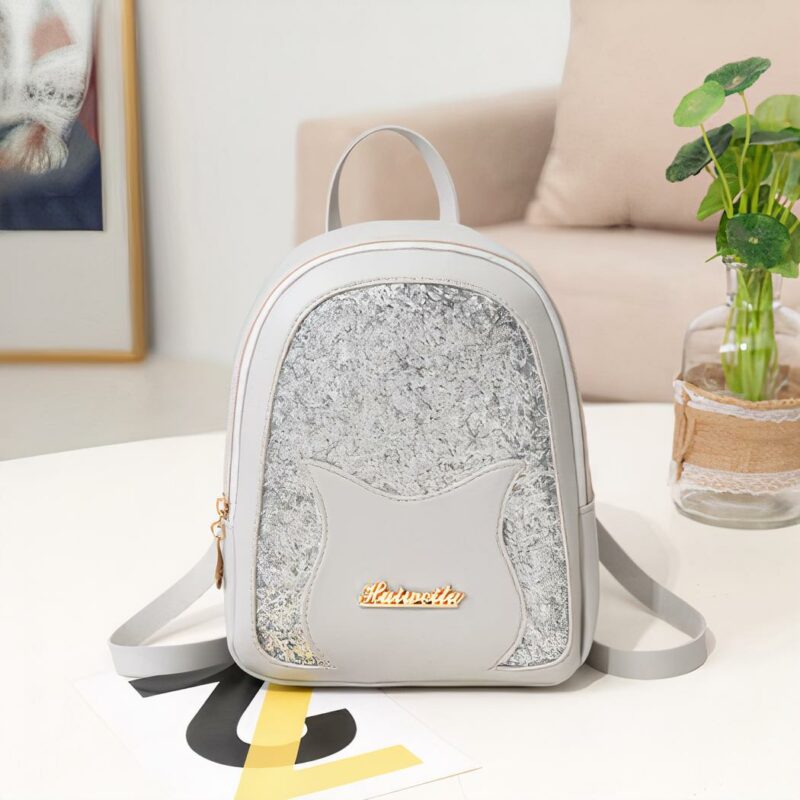 Mini zaino di paillettes per ragazza grigio con sfondo tavolo bianco con sfondo divano beige