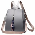 Zaino Oxford da donna rosa e grigio con ciondolo e sfondo bianco