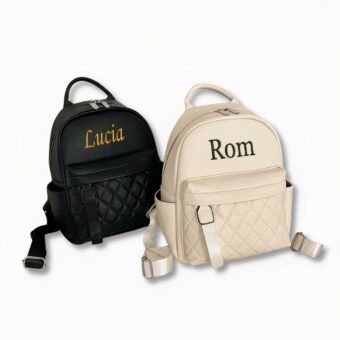 2 zaini in similpelle . uno bianco, l'altro nero, personalizzati con i nomi Lucia e Rom su sfondo grigio chiaro