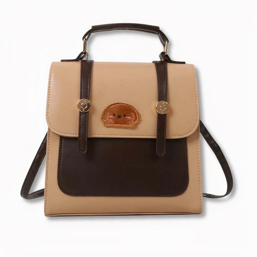 Zaino marrone e beige con distintivo del muso di cane sul davanti, su sfondo grigio chiaro