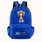 Foto di uno zaino di One Piece blu scuro. Lo zaino presenta un disegno sul davanti della versione manga di Luffy, che è in piedi con una maglietta rossa e pantaloncini di jeans. Tiene entrambe le mani in alto e il suo volto sembra felice. La tasca anteriore presenta il logo di One Piece con un motivo di teschio e ossa incrociate e una scritta blu. La borsa ha anche delle tasche laterali. Lo sfondo dell'immagine è grigio chiaro.