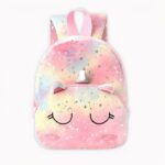 Zaino unicorno in rosa pastello, giallo e blu. Gli occhi dell'unicorno sono sulla tasca anteriore della borsa, lei chiude gli occhi e sopra di essi ci sono le orecchie e il corno argentato. Il materiale della borsa è felpato e ci sono stelle argentate ovunque. Lo sfondo è grigio chiaro.