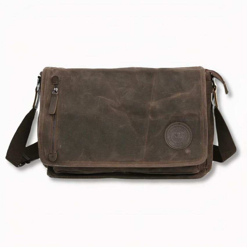 Cartella per studenti in tela marrone con tracolla e zip frontale a sinistra, su sfondo grigio chiaro