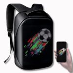 Sac à dos avec écran LED programmable, noir de forme rectangulaire avec bretelles rembourrées. Sur l'écran, un ballon de foot avec des traits de couleurs bleus, verts et rouges. A droite du sac, une main tenant un téléphone portable montrant le même motif que sur le sac à dos.