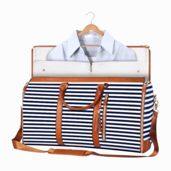 Sac de voyage rayé blanc et noir et détail marron, un peu ouvert sur le dessus avec une chemise qui en sort, sur fond blanc