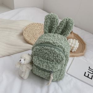 Morbido zaino verde coniglio con un letto bianco, un libro e un orsacchiotto sul fondo